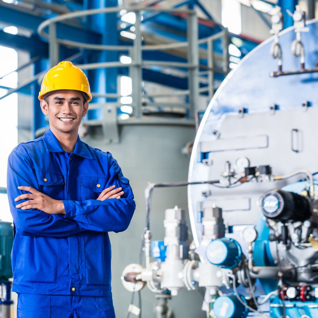 Engenheiro especialista da Master Hidráulica vestindo uniforme azul e capacete amarelo, de braços cruzados em ambiente industrial. Representa a equipe de suporte técnico qualificado.